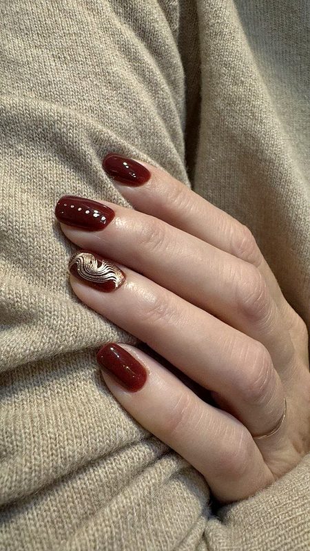 Manicura burdeos con detalle dorado